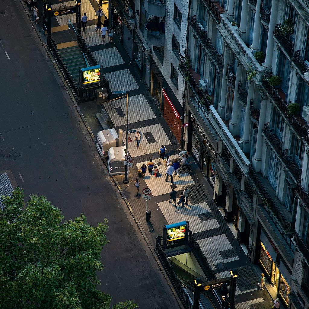 Straße im Abendlicht mit Passanten und Haltestellen